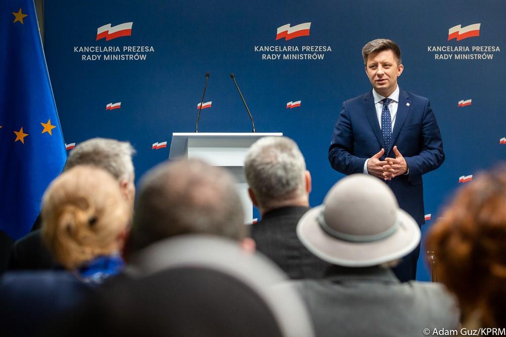 Szef kancelarii premiera Michał Dworczyk na tle loga KPRM.