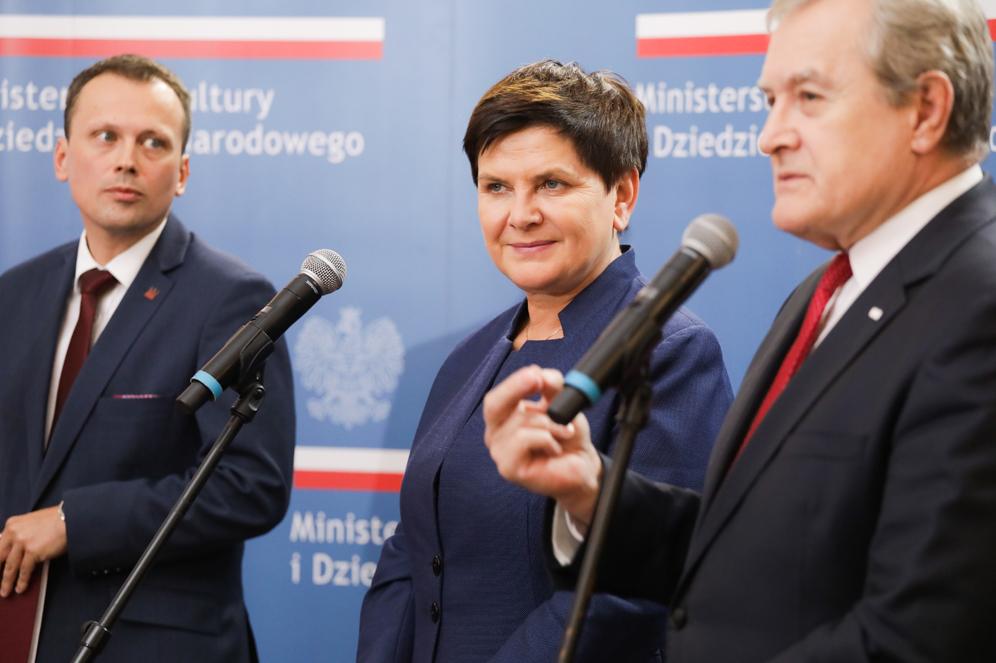 Ministrowie stoją przy mikrofonach.