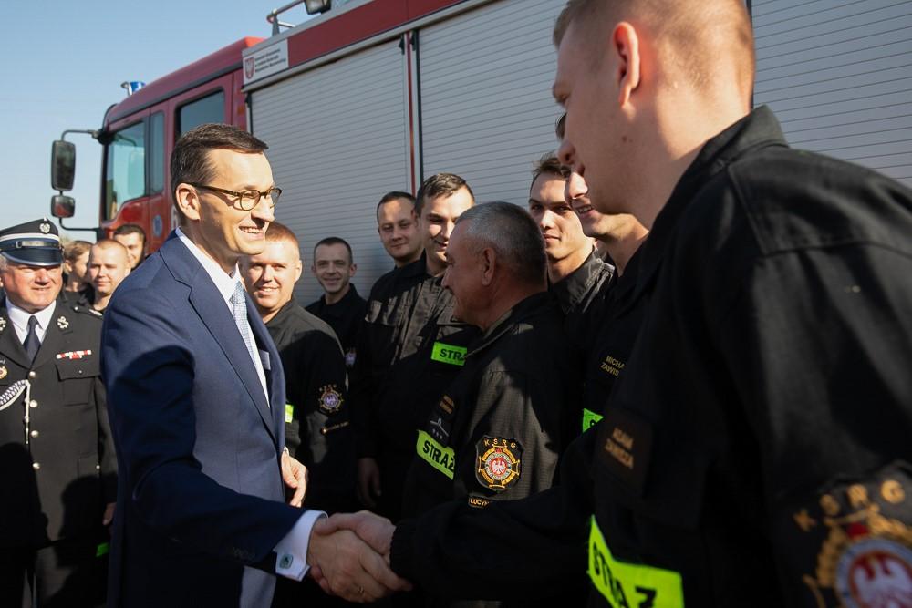 Premier Mateusz Morawiecki wita się ze strażakami.