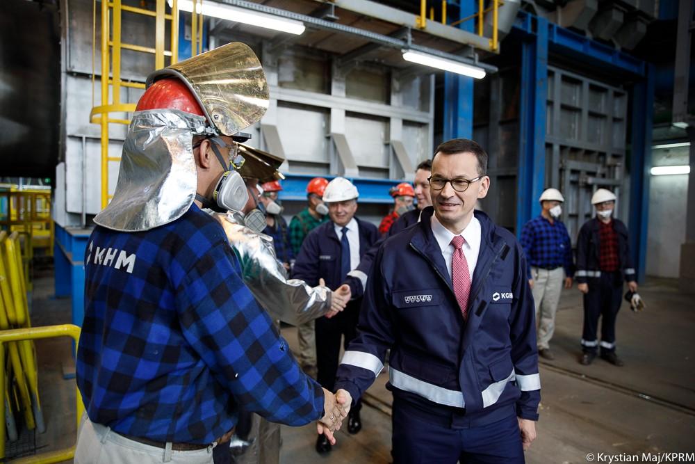 Premier Mateusz Morawiecki ściska dłoń pracownikowi. 