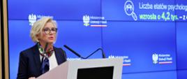 Wiceminister Machałek stoi za mównicą i mówi do dwóch mikrofonów.