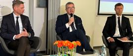 Wiceminister Wojciech Murdzek gościem konferencji „Od Edukacji do Biznesu”, wiceminister Wojciech Murdzek przemawia podczas konferencji, siedzi przy stole w towarzystwie innych prelegentów.