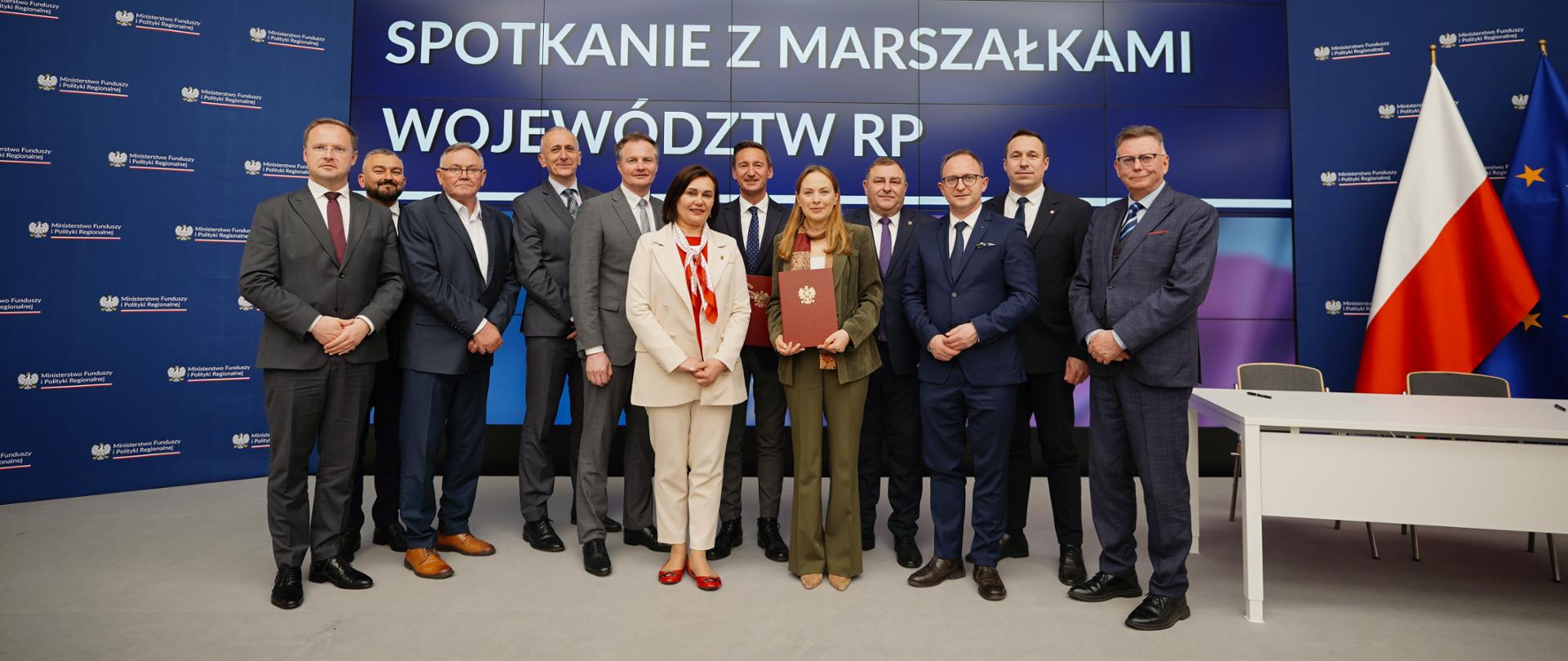 Grupa osób stoi na scenie. Wśród nich stoi minister Katarzyna Pełczyńska-Nałęcz.