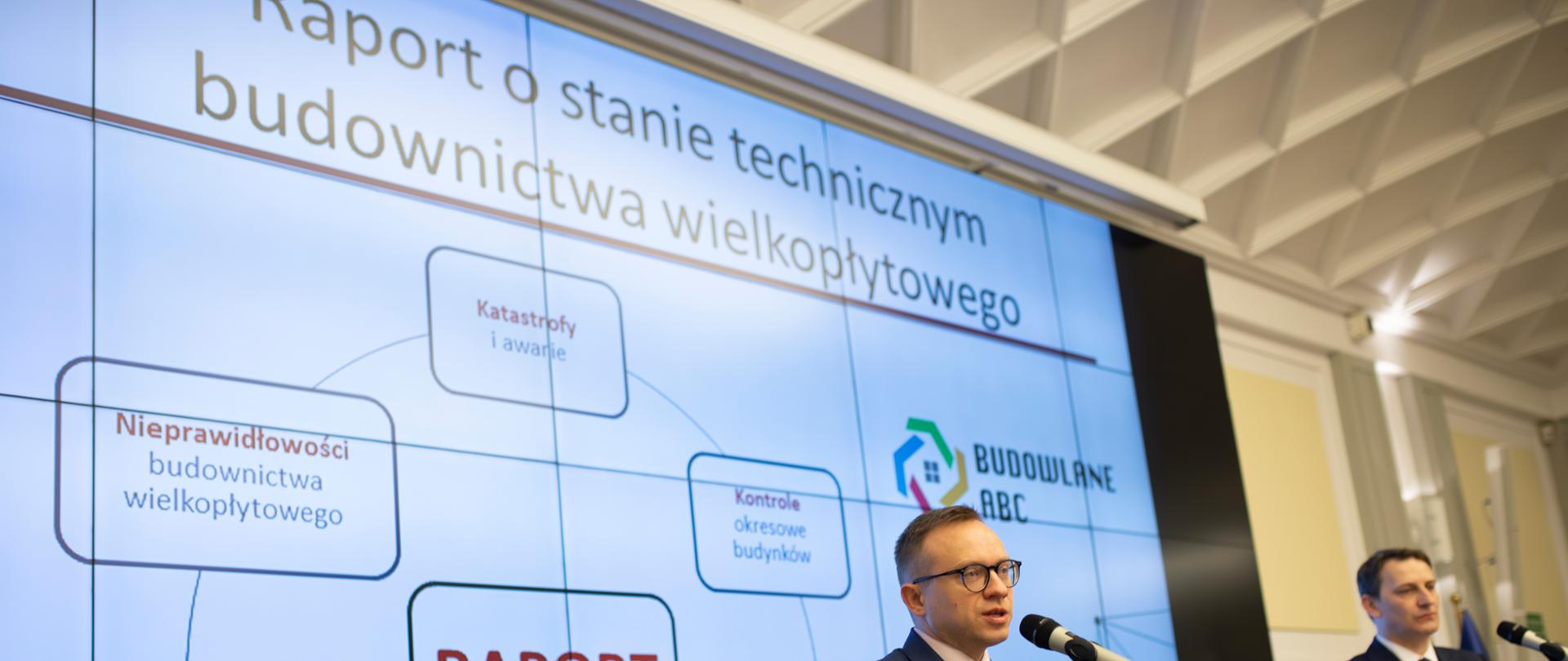Wiceminister Artur Soboń na tle prezentacji o raporcie dotyczącym wielkiej płyty