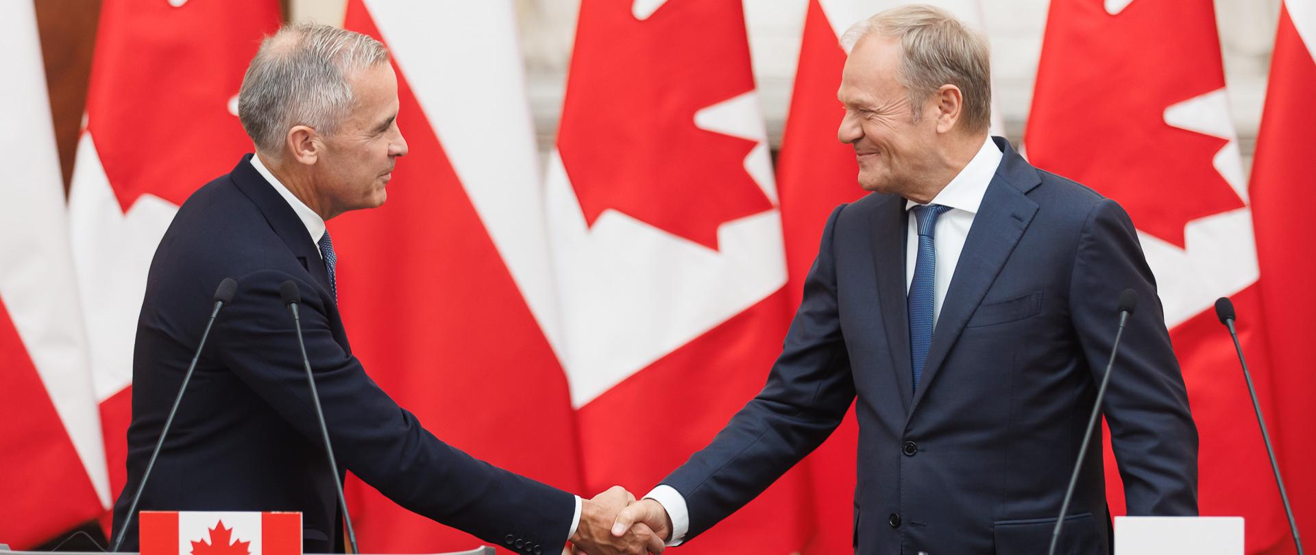 Premier Donald Tusk i Premier Kanady Mark Carney podczas wspólnego oświadczenia w Kancelarii Prezesa Rady Ministrów. W tle flagi obu państw.