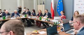 Pierwsze posiedzenie Komitetu Monitorującego Krajowy Plan Odbudowy - wiceminister funduszy i polityki regionalnej Marcin Horała siedzi przy stole i przemawia przez mikrofon, po jego lewej stronie siedzi dyrektor Departamentu Strategii w MFiPR Renata Calak