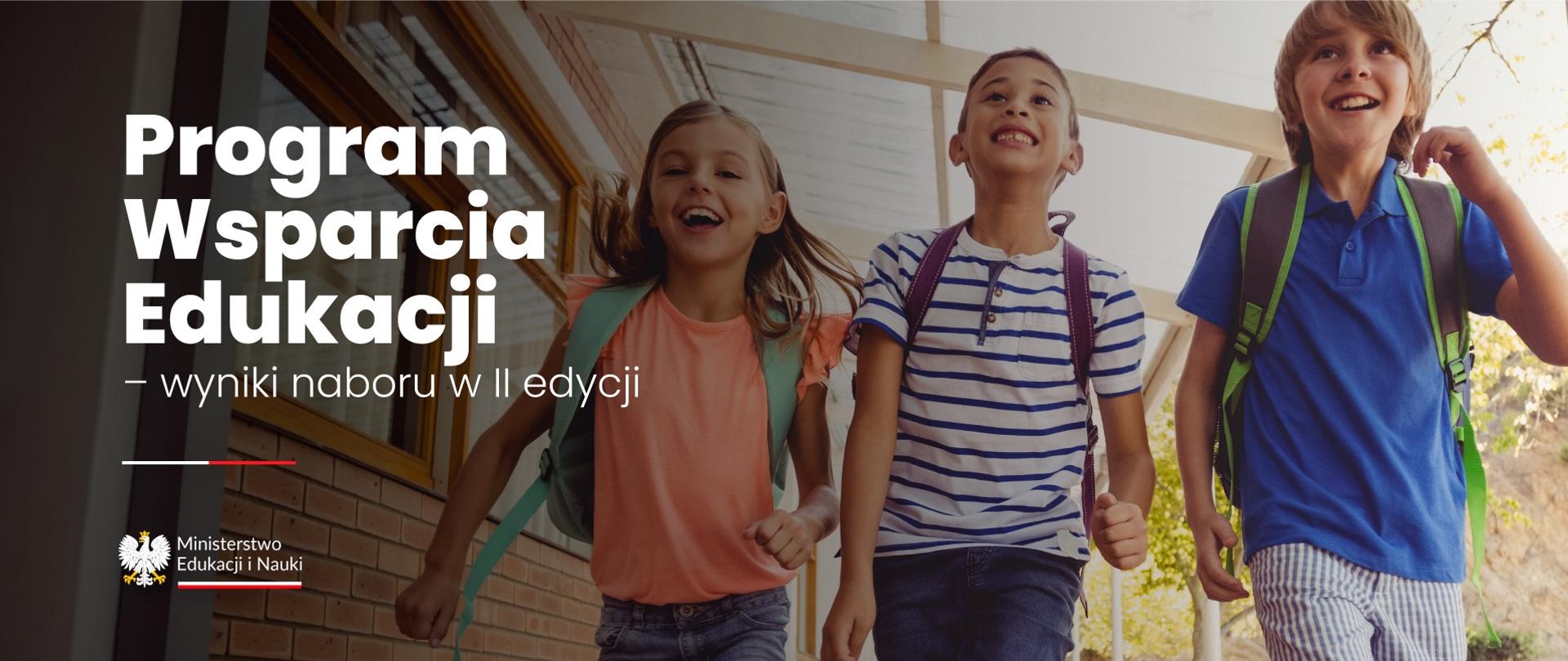 Troje roześmianych dzieci z tornistrami biegnie korytarzem, obok napis Program Wsparcia Edukacji - wyniki naboru w II edycji.