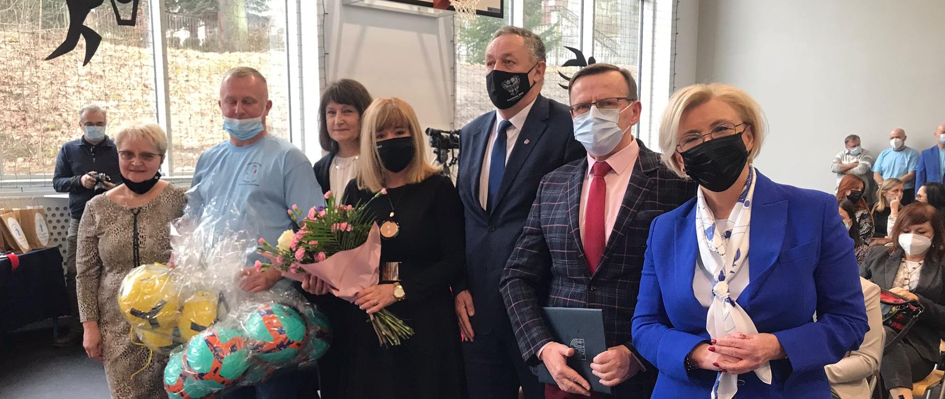 wiceminister Marzena Machałek stoi wraz z innymi uczestnikami wydarzenia w pierwszym rzędzie na sali gimnastycznej Otwarcie hali widowiskowo-sportowej z udziałem wiceminister Marzeny Machałek 