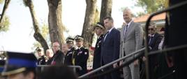 Przy schodach na podwyższeniu stoi minister Czarnek i dużo ludzi, niżej strażacy.
