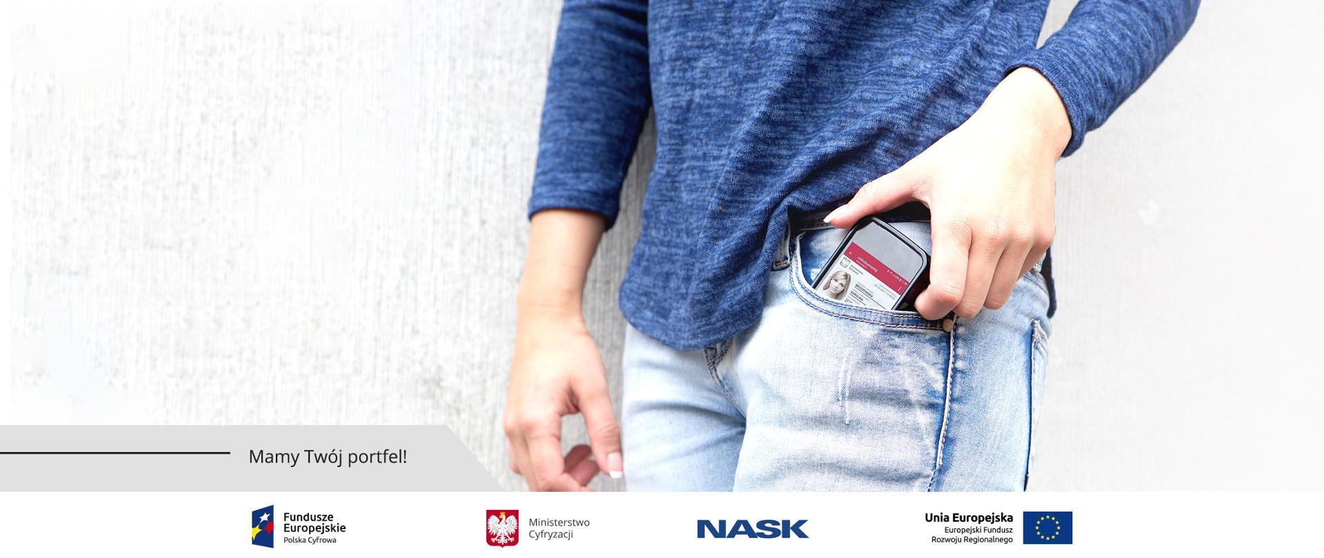 Zdjęcie kobiety (widok od połowy, zbliżenie na kieszeń) wyciągającej z kieszeni telefon. Na ekranie telefonu - screen aplikacji mObywatel.