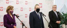 Uczestnicy konferencji prasowej stoją przed mikrofonami.