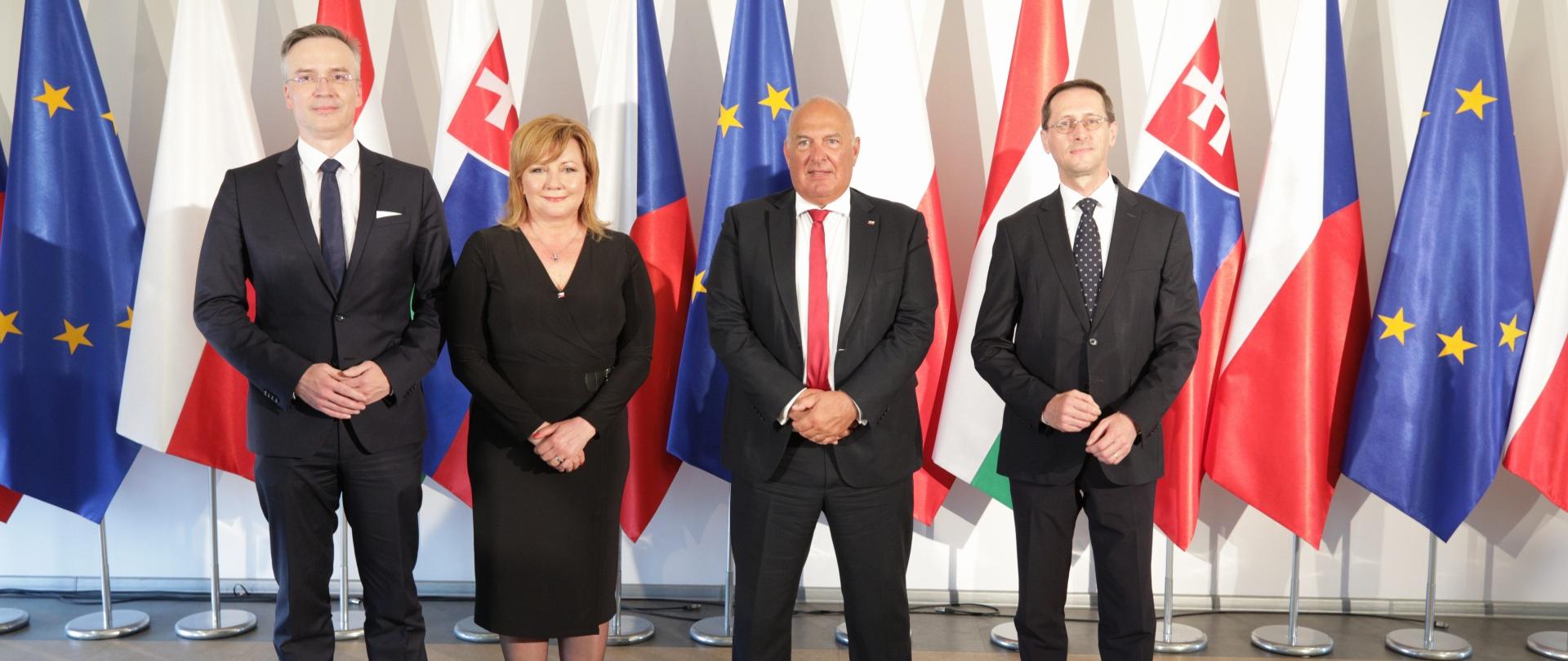 Uśmiechnięci ministrowie finansów państw Grupy Wyszehradzkiej na tle flag