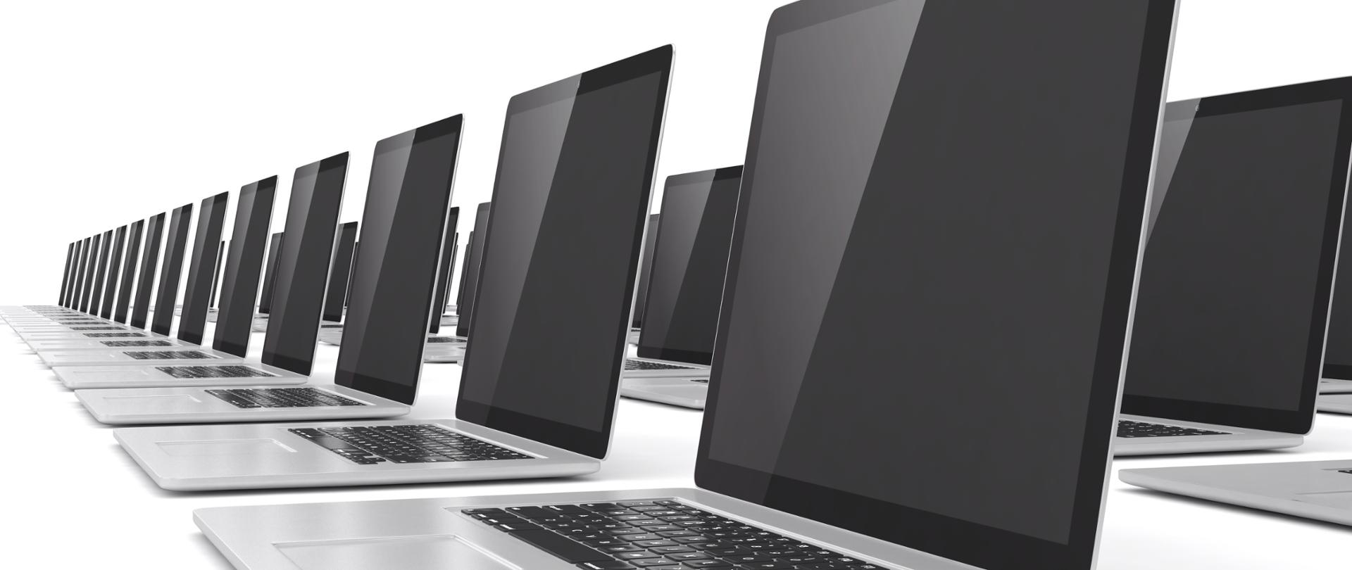 W kilku rzędach ustawione laptopy jeden za drugim