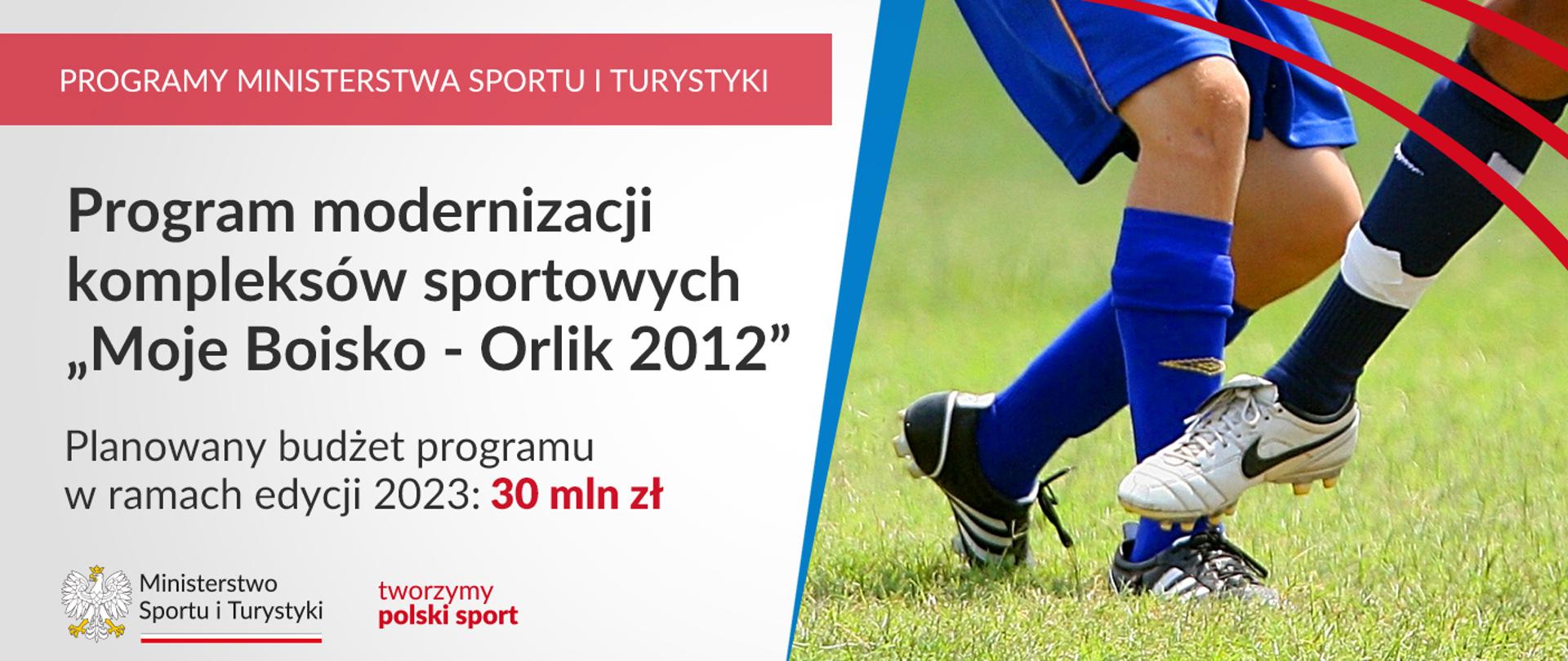 Na grafice od lewej strony znajdują się napisy: "Programy Ministerstwa Sportu i Turystyki", "Program modernizacji kompleksów sportowych "Moje Boisko - Orlik 2012", "Planowany budżet programu w ramach edycji 2023: 30 mln zł" oraz logotyp Ministerstwa Sportu i Turystyki, na który składa się godło Polski, napis "Ministerstwo Sportu i Turystyki" podkreślony biało-czerwoną wstążką i logotyp z napisem "tworzymy polski sport". Po prawej stronie grafiki znajduje się fragment zdjęcia ilustrującego nogi piłkarzy rywalizujących na murawie.