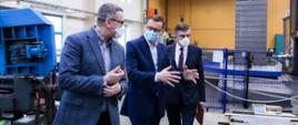 Premier oraz dwóch mężczyzn idą w siedzibie firmy.
