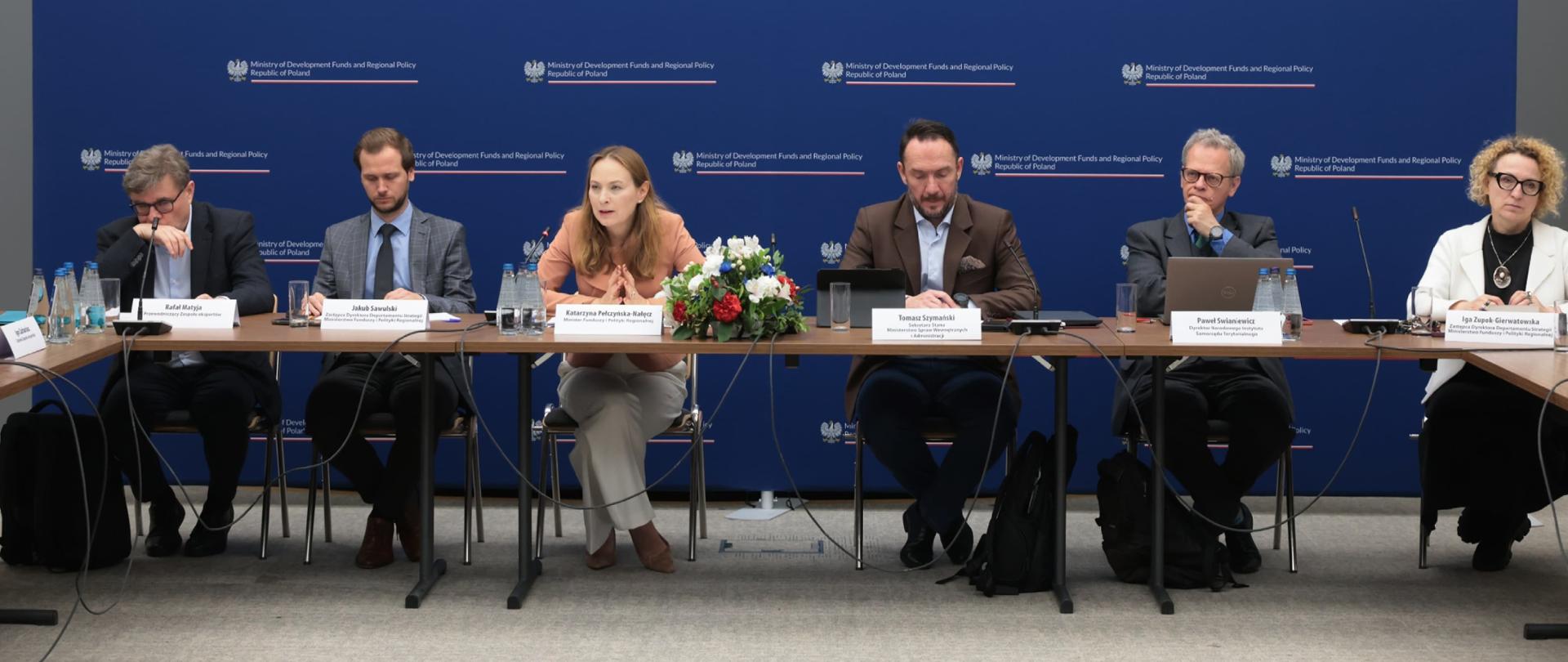 W sali konferencyjnej na tle ścianki MFiPR sześć osób siedzi przy stole. Trzecia od lewej minister Katarzyna Pełczyńska-Nałęcz.