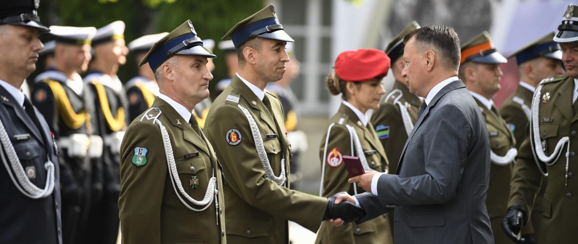 Minister Mariusz Błaszczak wręcza żołnierzowi Dowództwa Garnizonu Warszawa wyróżnienie z okazji Święta Wojska Polskiego
