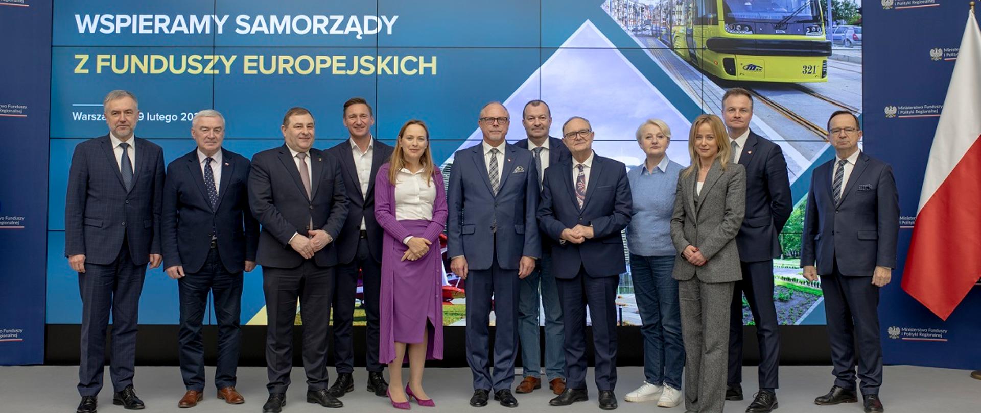 Minister funduszy i polityki regionalnej z marszałkami województw na spotkaniu podsumowującym realizację programów regionalnych, minister stoi na scenie z marszałkami, po jej lewej stronie stoi wiceminister funduszy i polityki regionalnej Jacek Protas