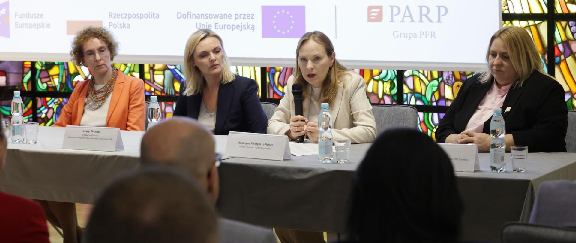 W sali konferencyjnej przy stole siedzą cztery kobiety. Druga z prawej minister Katarzyna Pełczyńska-Nałęcz z mikrofonem. Przed nimi publiczność.