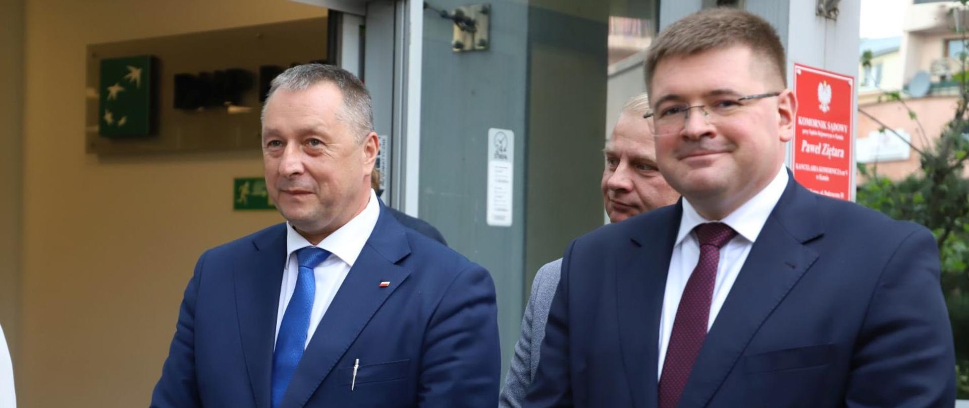 wiceminister przed budynkiem wraz z innym uczestnikiem uroczystości 