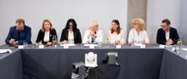 Uczestnicy debaty siedzą za stołem przykrytym szarym materiałem.
