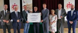Grupa osób trzymających duży czek