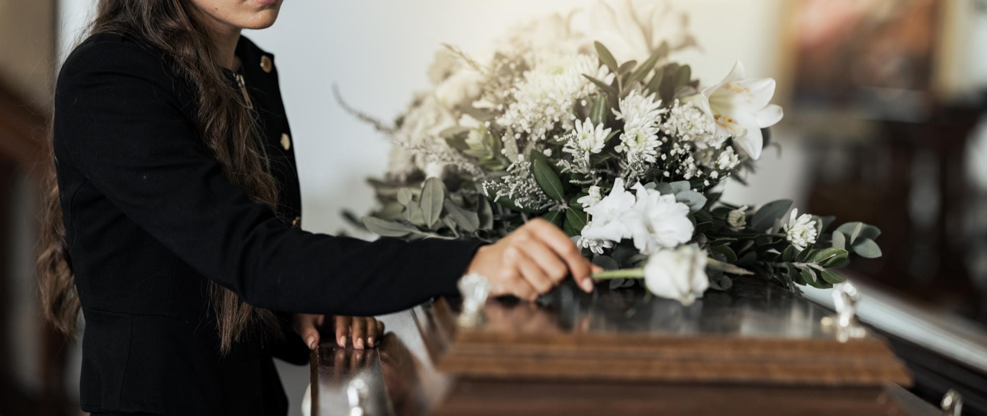 Funeral, sad and woman with flower on coffin after loss of a loved one, family or friend. Grief, de.