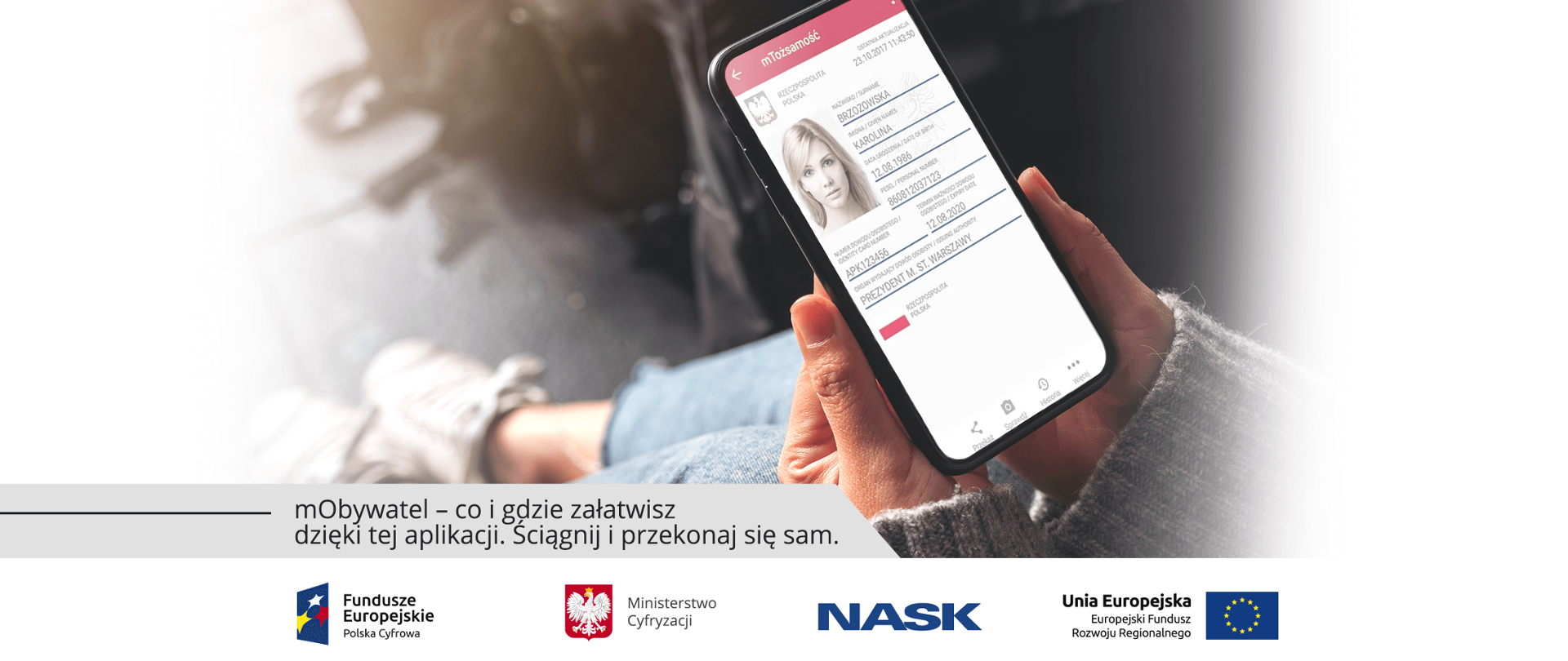 Kobieta siedzi i trzyma w dłoni telefon z wyświetloną wizualizacją aplikacji mObywatel