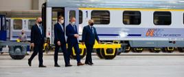 Premier idzie na tle pociągu.