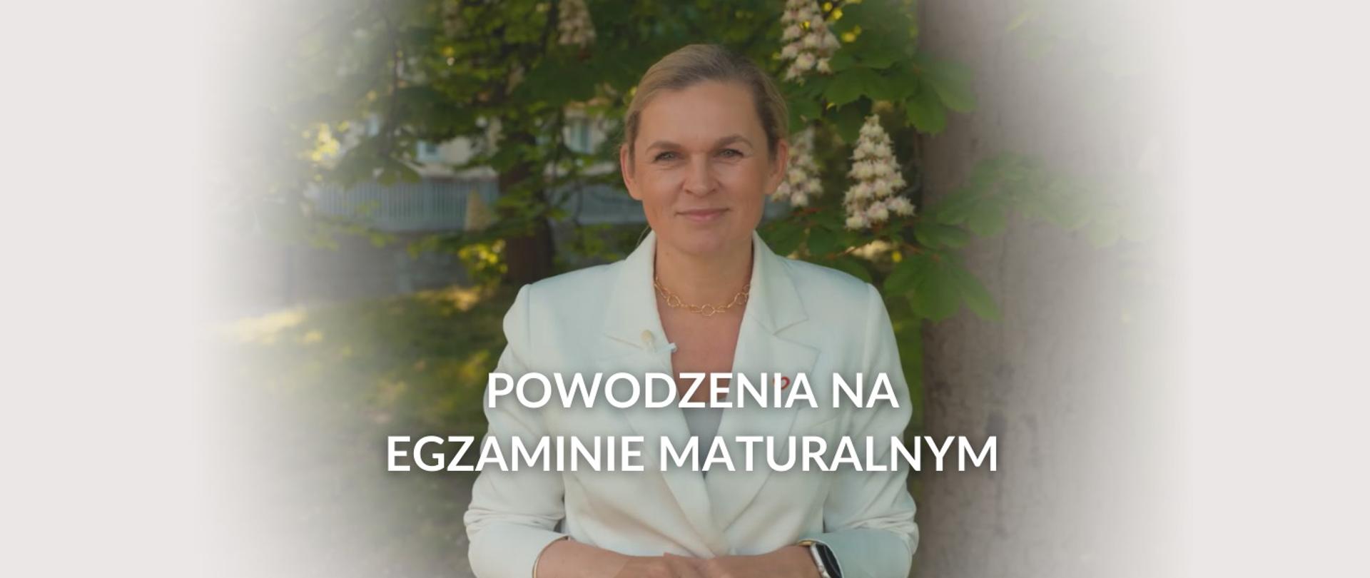 Powodzenia na egzaminie maturalnym, napis na zdjęciu przedstawiającym minister Barbarę Nowacką na tle kasztana, która składa życzenia dla maturzystów