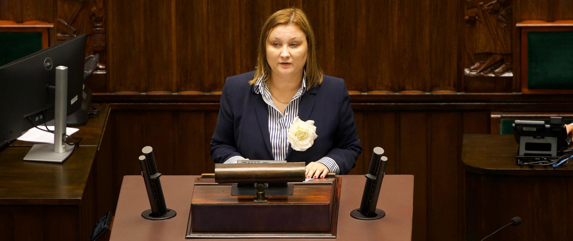 Zdjęcie przedstawia Podsekretarz Stanu Paulinę Piechnę-Więckiewicz przemawiającą przy mównicy sejmowej
