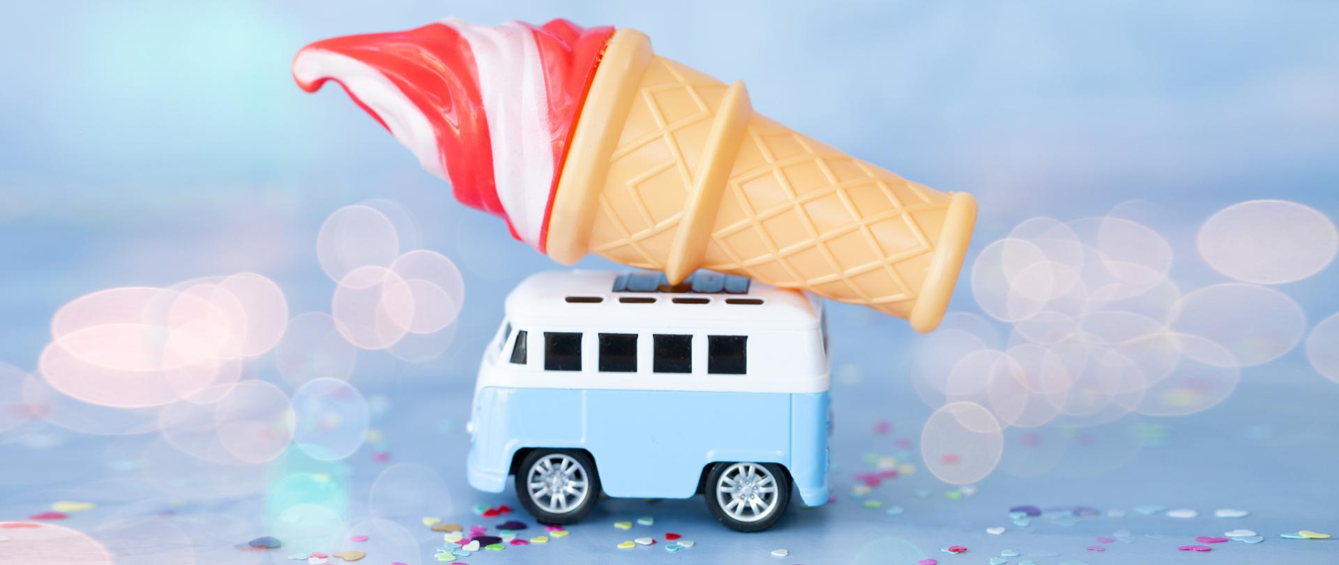 Na obrazku, na niebieskim tle widać zabawkowy samochodzik – błękitną lodziarnię z lodem w wafelku na dachu.