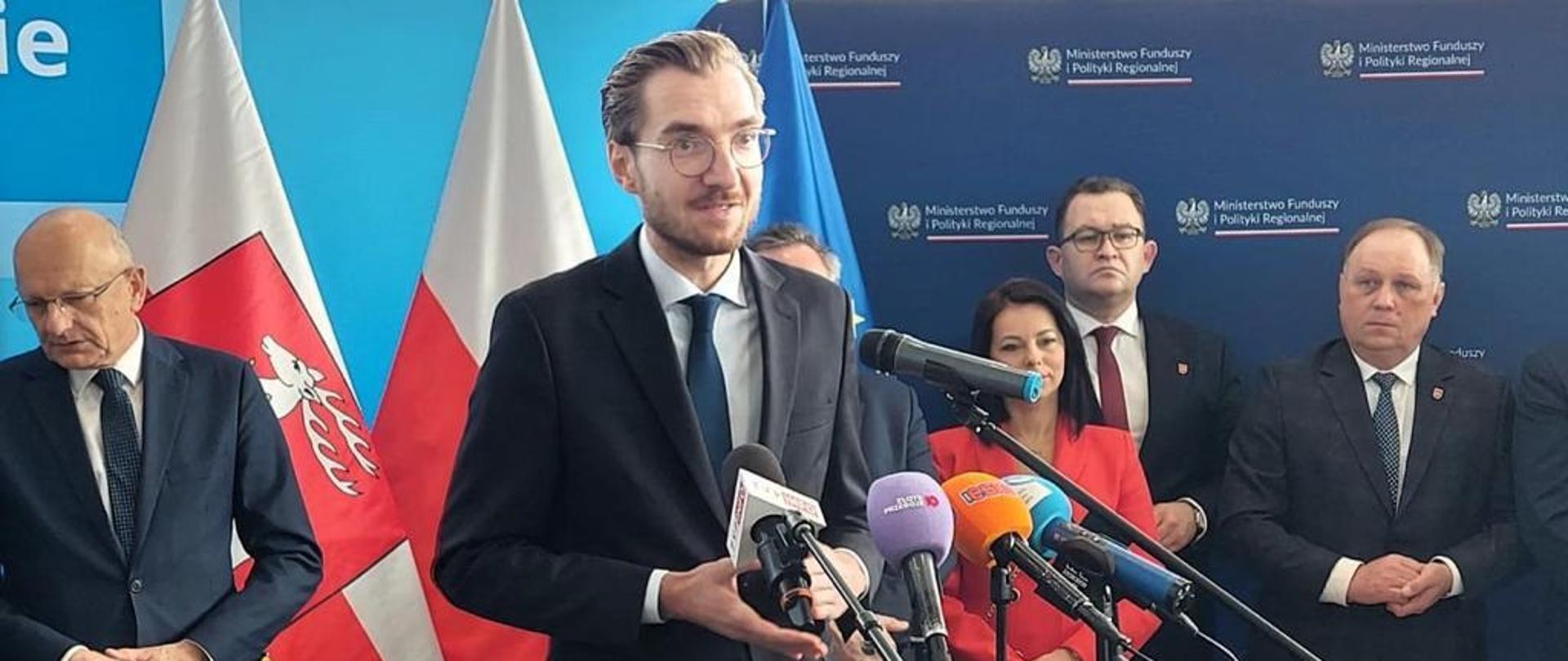 Wiceminister funduszy i polityki regionalnej Jan Szyszko stoi przy mikrofonach i przemawia, za jego plecami po lewej stoi prezydent Lublina Krzysztof Żuk