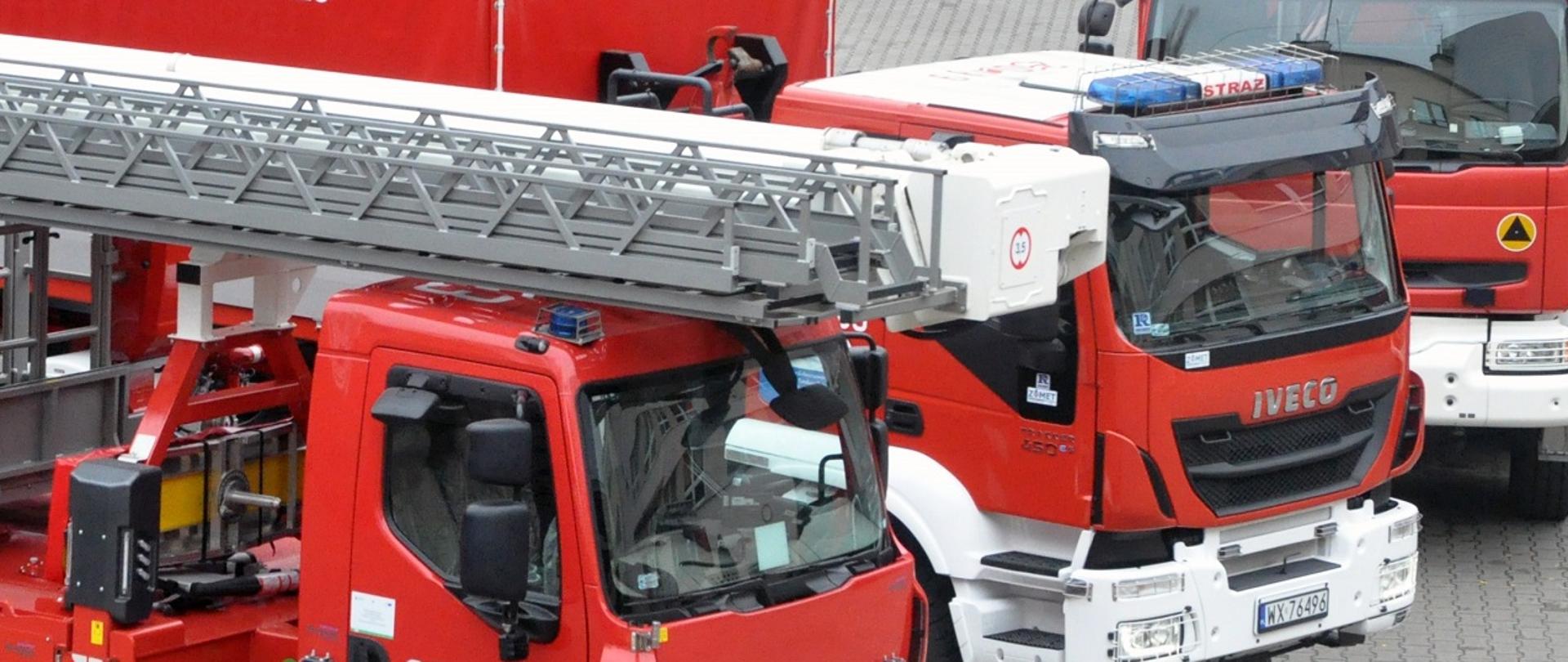 Na zdjęciu widać częściowo trzy samochody ciężarowe Państwowej Straży Pożarnej.