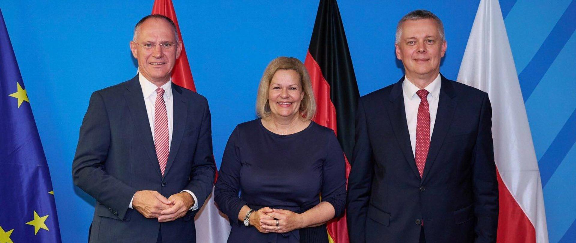 Od lewej ministrowie spraw wewnętrznych Austrii, Niemiec i Polski, niebieskie tło i flag tych krajów 