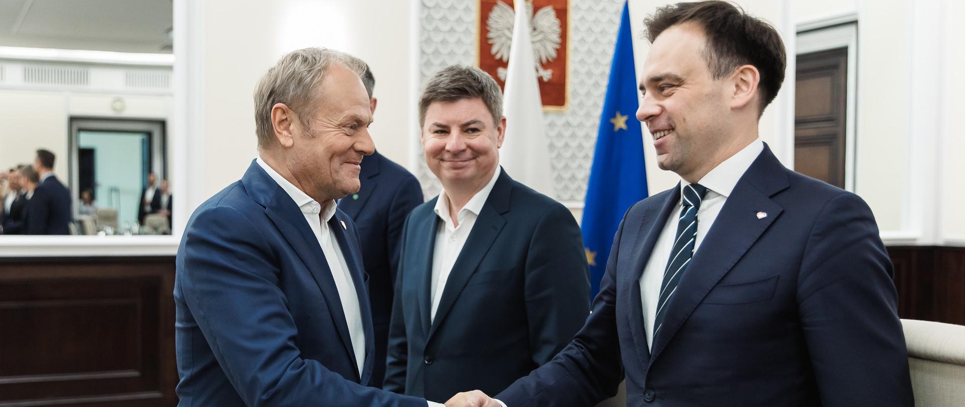 Prezes Rady Ministrów Donald Tusk wita się z Ministrem Finansów Andrzejem Domańskim podczas posiedzenia Rady Ministrów. W tle Szef Kancelarii Prezesa Rady Ministrów Minister Jan Grabiec.