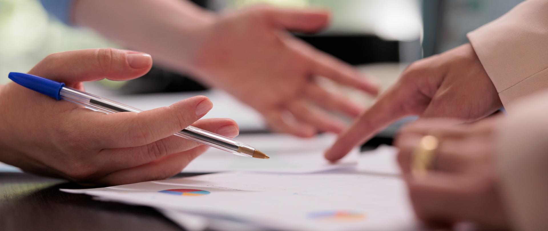 Coworkers analyzing financial report on meeting, planning company budget, close up on hands, woman pointing on charts. Colleagues teamwork, start up project investement briefing concept