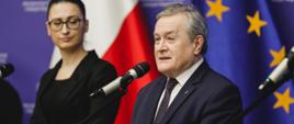Minister kultury i dziedzictwa narodowego Piotr Gliński i wiceminister klimatu i środowiska Małgorzata Golińska na konferencji prasowej podczas podpisania porozumienia w sprawie realizacji wybranych zadań z programu Fundusze Europejskie na Infrastrukturę, Klimat, Środowisko 2021–2027, ministrowie stoją przy mikrofonach, za ich plecami telebim z logo MFiPR