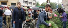 Na zdjęci widoczny jest Minister Sportu i Turystyki Kamil Bortniczuk składający wieniec pod Pomnikiem Małego Powstańca. W tle znajduje się tłum ludzi oraz pan w mundurze harcerskim na wózku inwalidzkim.