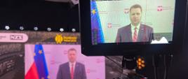 Na pierwszym planie przemówienie Ministra Czarnka podczas Gali Finałowej Studenckiego Nobla (widok z ekranu tableta). W tle odwzorowanie na ścianie wizyjnej.