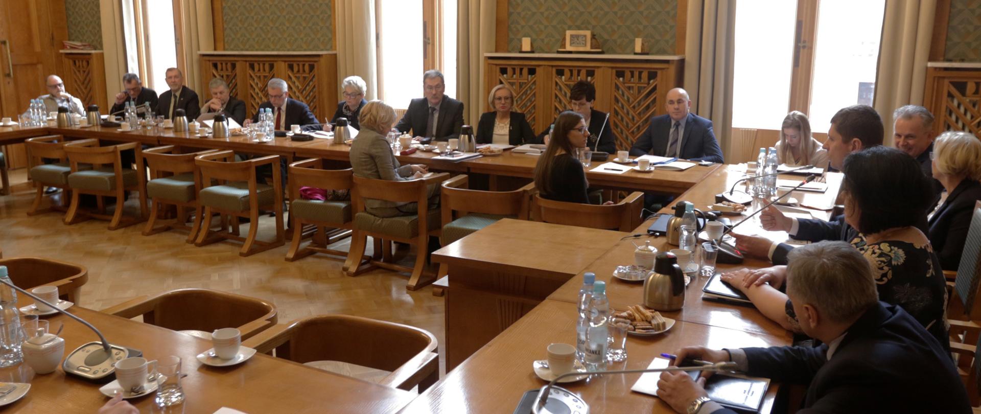 Na sali siedzą uczestnicy spotkania. Po prawej stronie minister edukacji wraz ze współpracownikami.