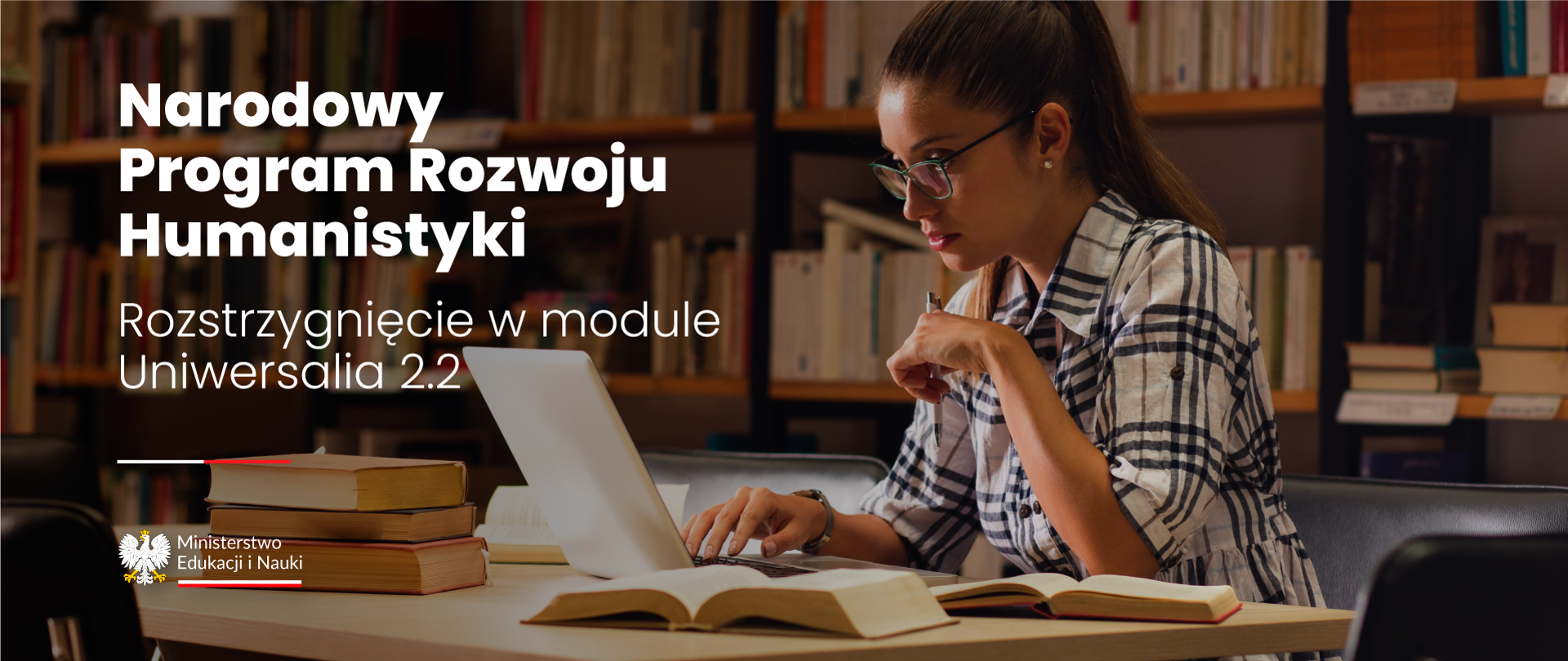 Dziewczyna w okularach i koszuli w kratę siedzi w bibliotece z otwartym laptopem. Po prawej stronie napis Narodowy Program Rozwoju Humanistyki – rozstrzygnięcie w module Uniwersalia 2.2