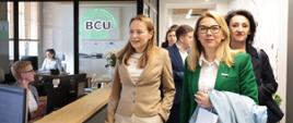 
Minister funduszy i polityki regionalnej Katarzyna Pełczyńska-Nałęcz idzie korytarzem w Branżowym Centrum Umiejętności (BCU) Przemysłu Drzewnego w Kaliszu, obok niej stoją osoby, z którymi zwiedza BCU
