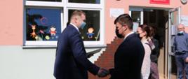 Wizyta ministra Przemysława Czarnka w Warce. Minister przed szkołą wita się z uczniami.