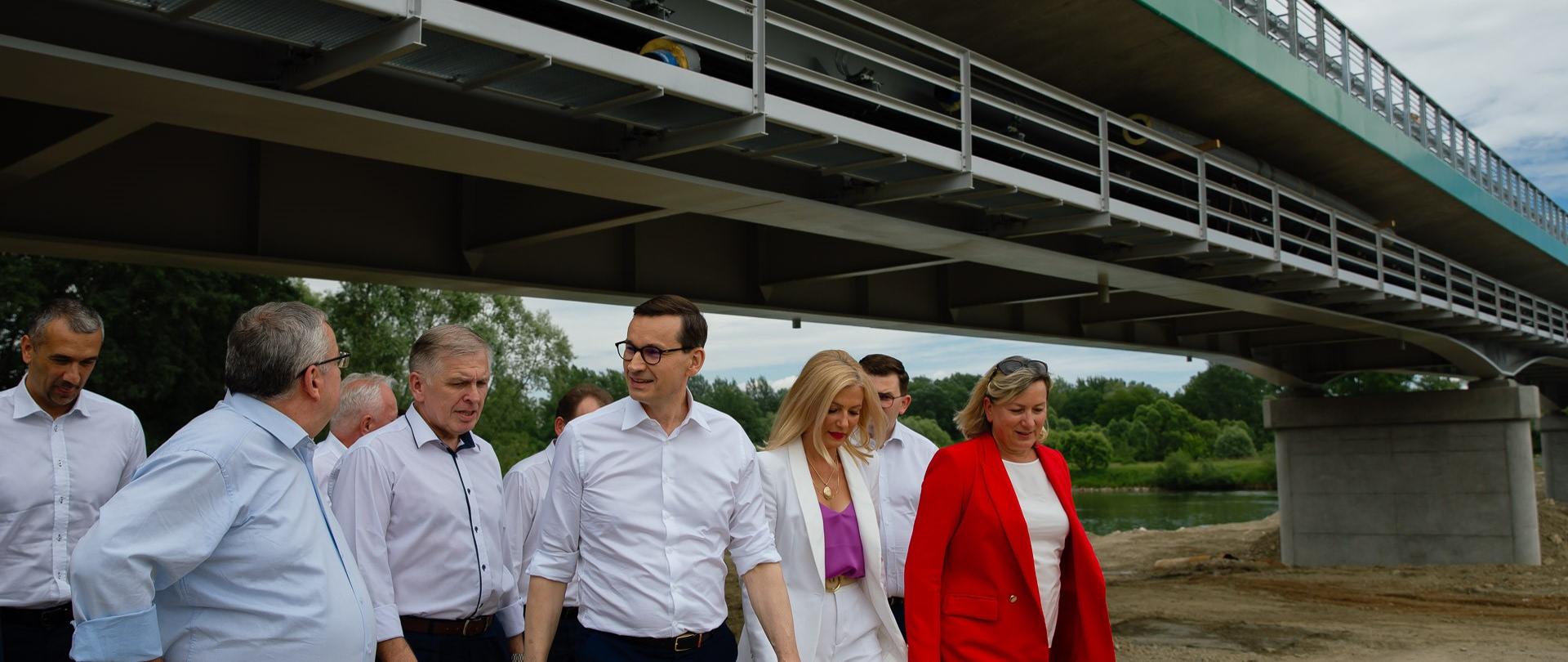 Premier oraz pozostali idą, w tle most.