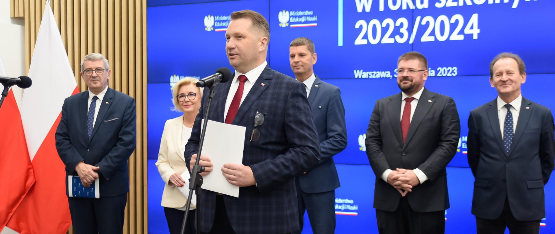 Konferencja prasowa z udziałem ministra Przemysława Czarnka i kierownictwa MEiN. Do mikrofonu przemawia minister Czarnek za nim stoją od lewej wiceministrowie: Wojciech Murdzek, Marzena Machałek, Dariusz Piontkowski, Tomasz Rzymkowski, Włodzimierz Bernacki.
