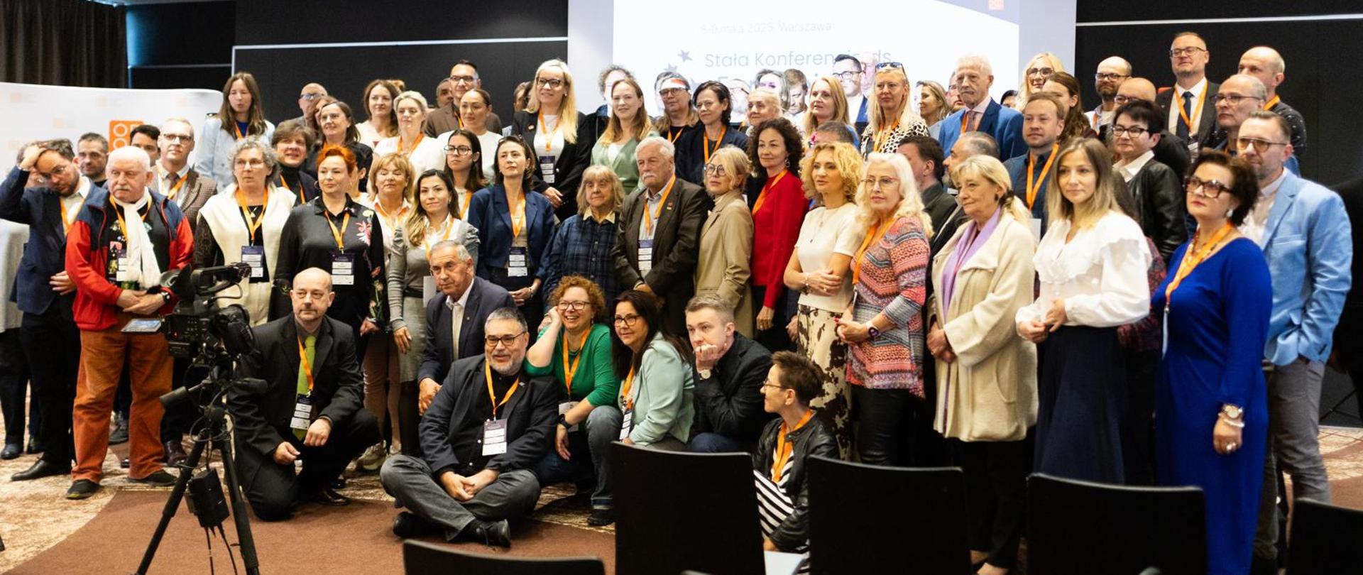 Grupa osób w sali konferencyjnej pozuje do zdjęcia