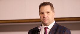 Minister Czarnek mówi do mikrofonu na stojaku.