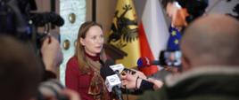 Na zdjęciu Minister Katarzyna Pełczyńska-Nałęcz przed mikrofonami odpowiada na pytania dziennikarzy