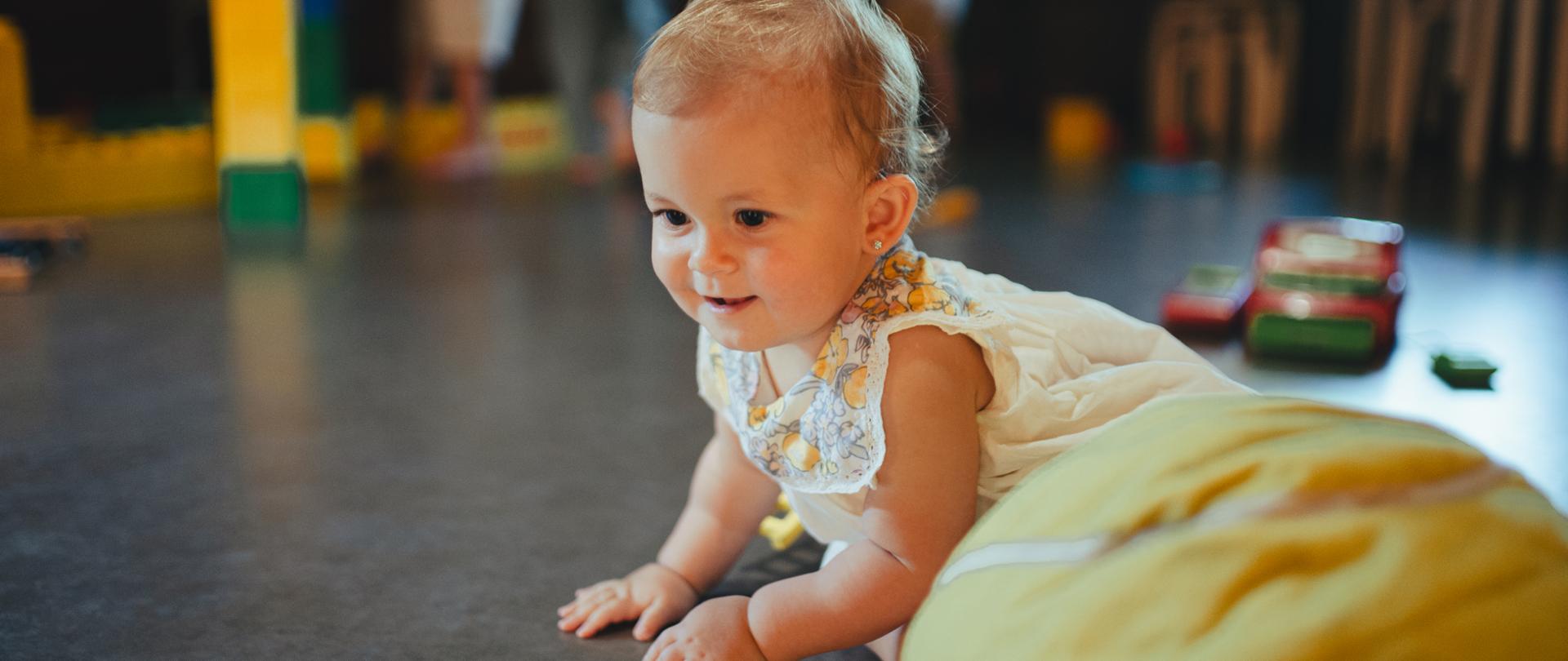 Portrait of baby crawling, exploring the interior of the children's room. The little child playing in interior kids' playground at a restaurant. Concept of kids-friendly hotel.